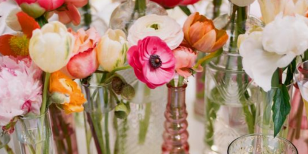 Slim glass vases of flowers on a white table